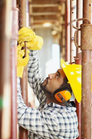 latin american construction worker fastening girder. Side view
