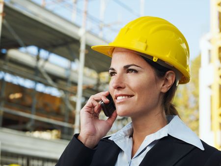 female engineer talking on mobile phone in construction siteの写真素材