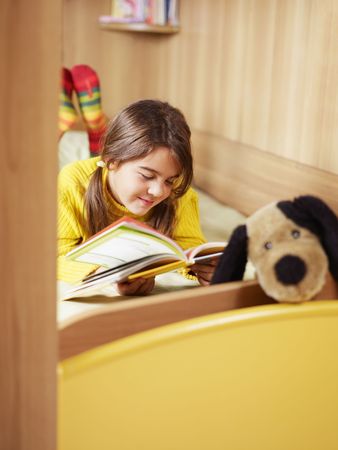 girl lying on bed and reading book. Copy spaceの写真素材