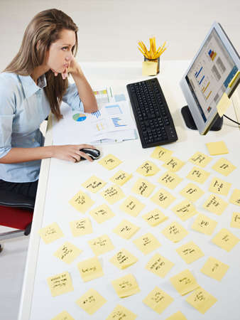 tired business woman with adhesive notes on table. High angle viewの写真素材