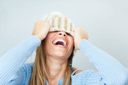 portrait of young woman laughing while covering face with wool hat. Horizontal shape, Copy space
