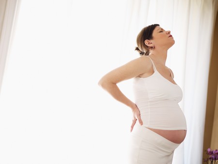 italian 7 months pregnant woman massaging her back. Horizontal shape, side view, copy spaceの写真素材