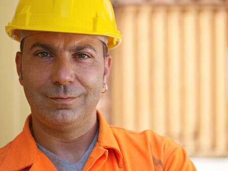 portrait of mid adult worker standing near cargo containers and looking at camera. Horizontal shape, front view, copy spaceの写真素材
