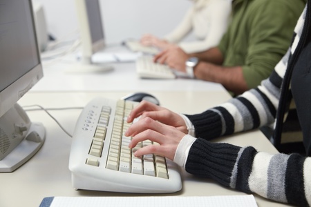 Closeup of caucasian female student typing on keyboard in computer lab. Horizontal shape, side viewの写真素材