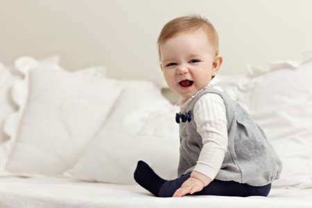 portrait of 6 months female child playing on bed and smiling at camera. Horizontal shape, side view,...