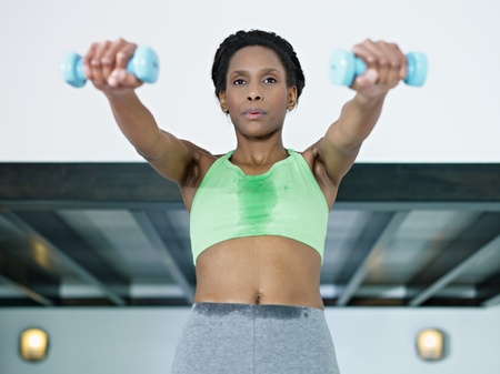 young african american woman in green sportswear doing weight lifting in fitness club. Horizontal...