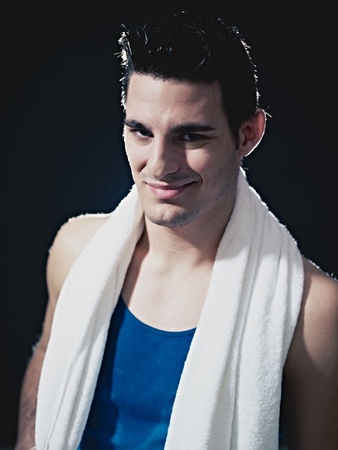 portrait of confident caucasian male in sportswear, looking at camera and smiling on black background. Vertical shape, waist up, front viewの写真素材