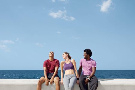 caucasian, hispanic and african american friends smiling and having fun near the sea. Horizontal...