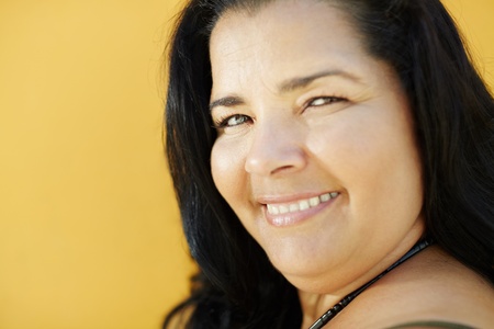 portrait of latin american 50 years old overweight woman smiling on yellow background. Head and shoulders, copy space の写真素材