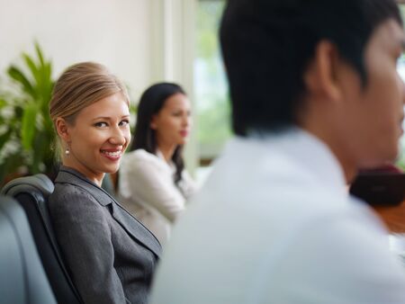 Beautiful young blonde woman working as manager and smiling at camera during business meeting with...