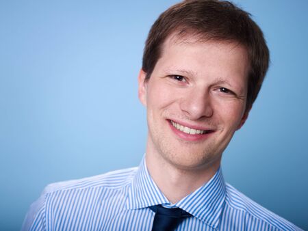 Portrait of mid adult business smiling at camera with arms crossed against blue background. Copy spaceの写真素材