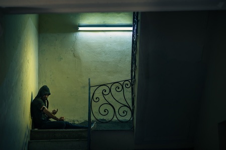 Social issues and drug abuse, young man injecting heroin and sitting on stairs. Copy spaceの写真素材