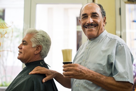 Old barber holding brush for talco and smiling to camera in old fashion barber shopの写真素材