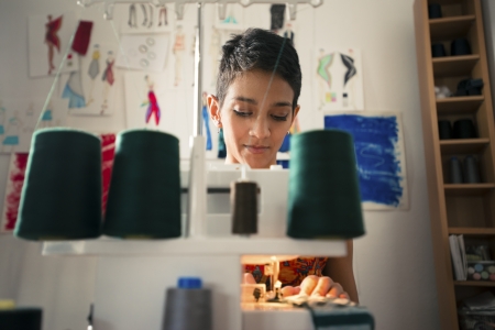 Small business and self-employed women, young hispanic woman working as fashion designer with sewing machine in studioの写真素材