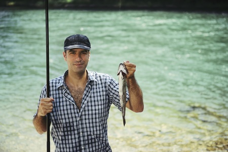 mid adult fisherman on holidays on river, relaxing and fishing trout. Copy space