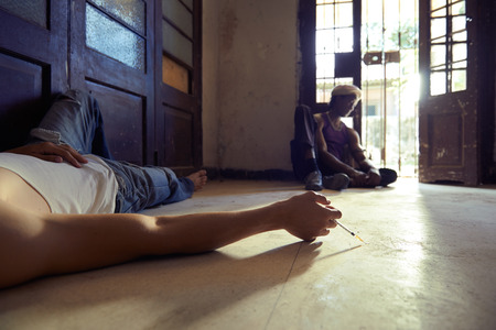 African american man and caucasian guy in overdose, injecting heroine with syringe and lying on pavementの写真素材