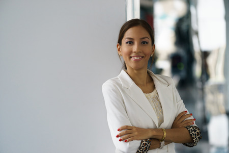 Portrait of happy and self confident latina businesswoman in tailleur, leaning with arms crossed on...