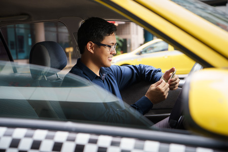 Asian man working as taxi driver in yellow car, with female client paying cash and leavingの写真素材