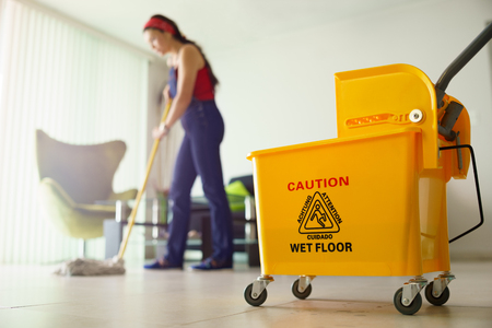 Young hispanic woman at home, doing chores and housekeeping, wiping floor with water in living room