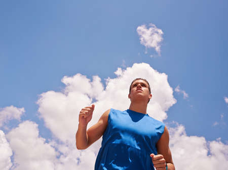 Young people doing sport activities, man runner jogging against blue sky. Copy space. Concept of leisure, health, recreation, fitness, lifestyle, exercising, workoutの写真素材