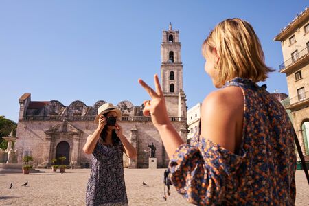Female friends on holidays, people traveling, young women having fun on vacation, two happy girls smiling in Havana, Cuba, taking pictures with camera near Cuban monument.の写真素材