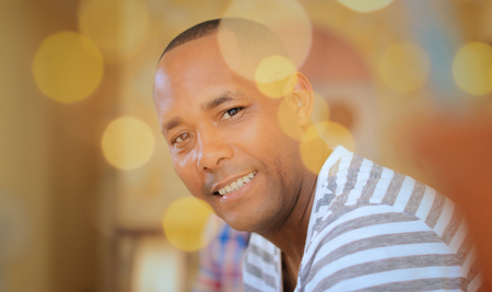 Portrait of homosexual adult man. Happy hispanic gay smiling at camera, sitting on sofa at home.の写真素材