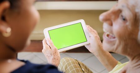 Family relationship with grandmother and granddaughter. Grandma using tablet with female grandchild. Happy old woman and little girl using computer with Chroma Key monitorの写真素材