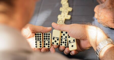 Retired people, seniors and free time. Old latino men having fun and playing game of domino in Cuba.の写真素材