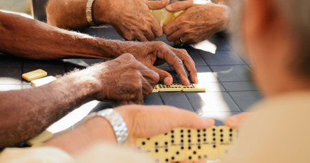 Retired people, seniors and free time. Old latino men having fun and playing game of domino in Cuba.の写真素材