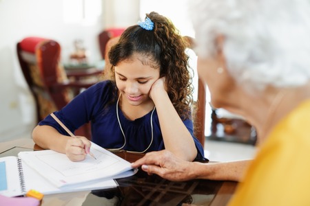 Elderly Woman Helping Little Girl Doing School Homework
