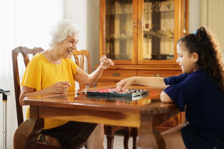 Grandma Playing Checkers Board Game With Granddaughter At Homeの写真素材