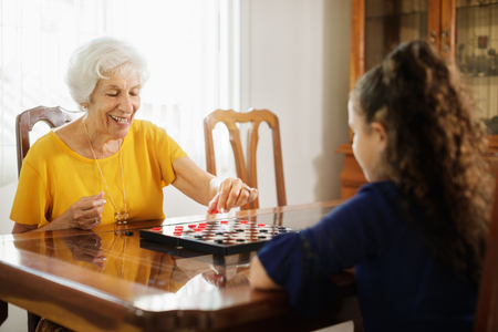 Grandma Playing Checkers Board Game With Granddaughter At Homeの写真素材
