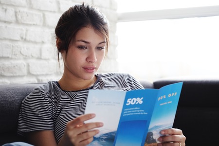 Woman Reading Travel Flye On Sofa At Homeの写真素材