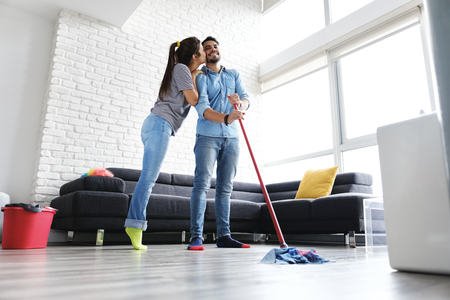 Man And Woman Kissing While Cleaning Homeの写真素材
