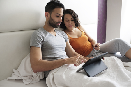 Young People In Bed Booking Holidays On Lineの写真素材