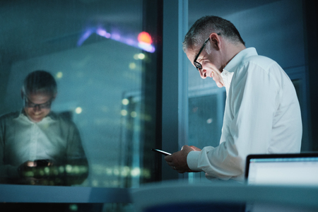 Happy Manager Using Smartphone In Dark Office At Nightの写真素材