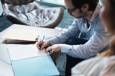Hispanic Manager Signing Document With Secretary In Business Officeの写真素材