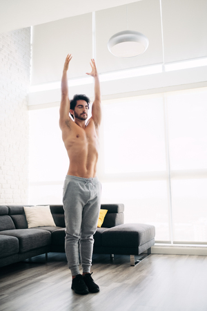 Man Practicing Yoga At Home Doing Sun Salutation Routineの写真素材