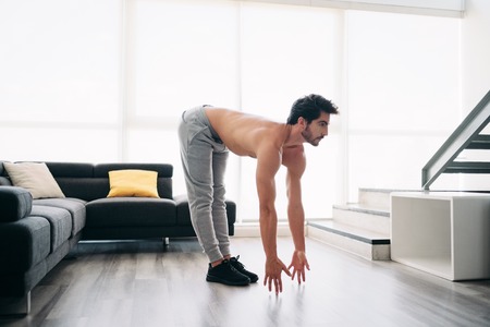 Man Practicing Yoga At Home Doing Sun Salutation Routineの写真素材