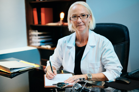 Portrait Of Female Doctor Working In Hospital Office Smiling At Cameraの写真素材