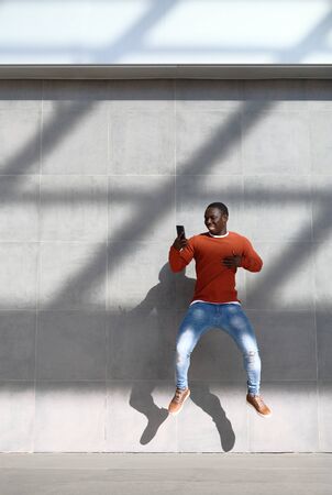 African Man Jumping For Joy Holding Phone
