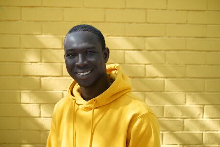 African Young Man Smiling With Yellow Wall In Backgroundの写真素材