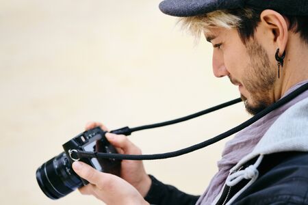 Hipster Street Photographer Reviewing Pictures On Mirrorless Camera Display