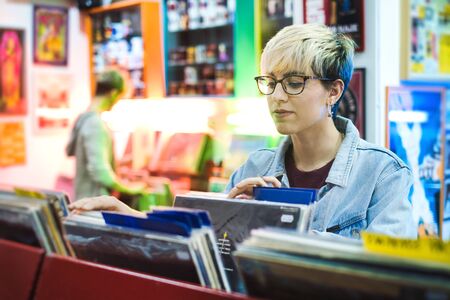 Young Woman Choosing Vintage Vinyl LP In Records Shopの写真素材