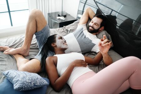 Happy Man And Woman With Beauty Mask On Bedの写真素材