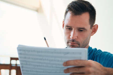 Man Composing Music Using Score Sheets To Write Notes Downの写真素材