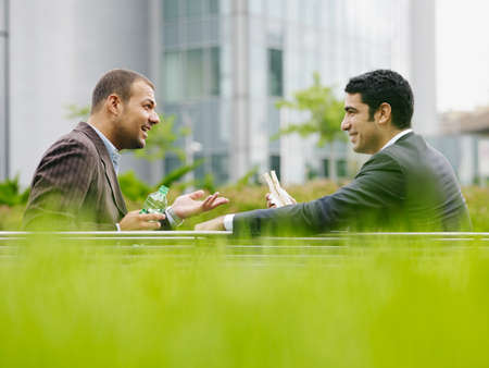 Two Business Men Enjoying Lunch Break Eating Sandwich Outdoorsの写真素材