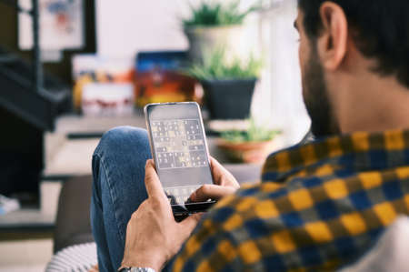 Young Man Playing Sudoku Game With App On Smartphoneの写真素材