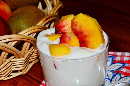 vanilla yogurt with peach pieces and fruit basketの写真素材