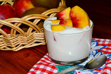 vanilla yogurt with peach pieces and fruit basketの写真素材